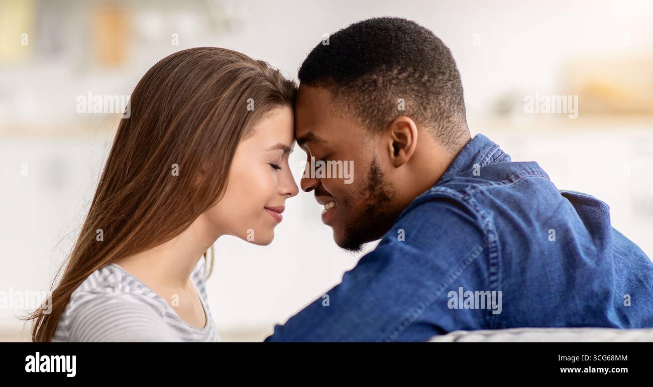 Momento romantico. Amorevole coppia interrazziale che si unisce a casa, primo piano Foto Stock