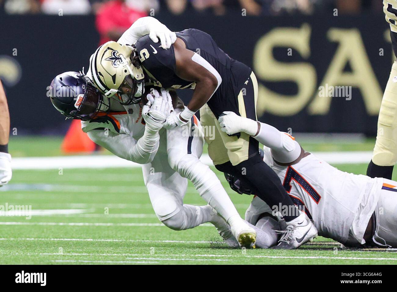 New Orleans, Stati Uniti. 23 agosto 2025. Il linebacker dei Denver Broncos Jonathon Cooper (0) e il defensive tackle Malcolm Roach (97) affrontarono entrambi il running back dei New Orleans Saints Kendre Miller (5) durante una gara di pre-stagione della NFL sabato 23 agosto 2025 al Caesars Superdome di New Orleans, Louisiana. (Foto di Peter G. Forest/Sipa USA) credito: SIPA USA/Alamy Live News Foto Stock