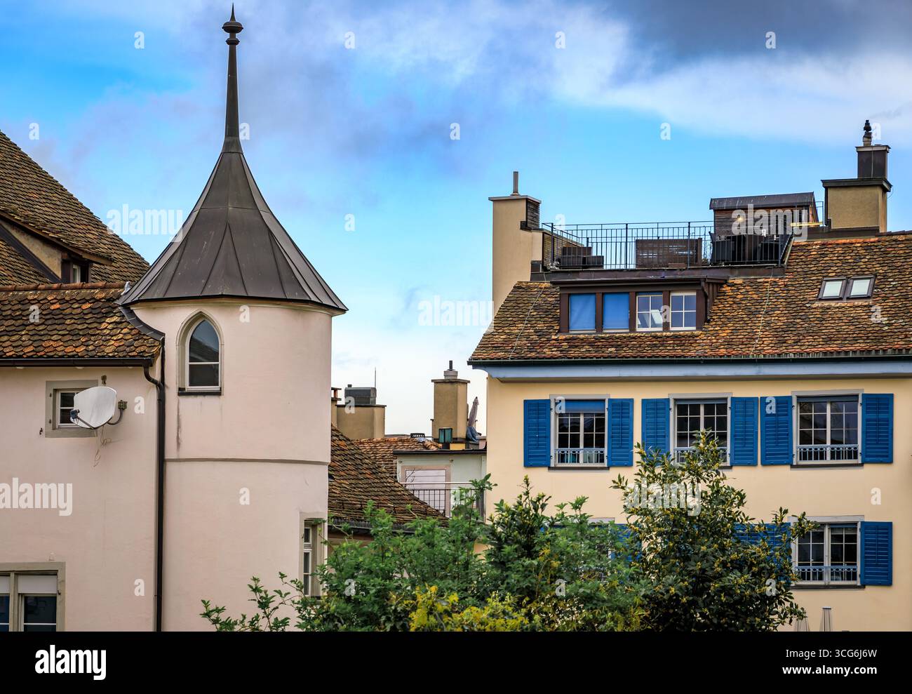 Vista ravvicinata di un edificio storico con torretta e di una casa classica con persiane in una giornata nuvolosa nella città vecchia o Altstadt, Zurigo, Svizzera Foto Stock