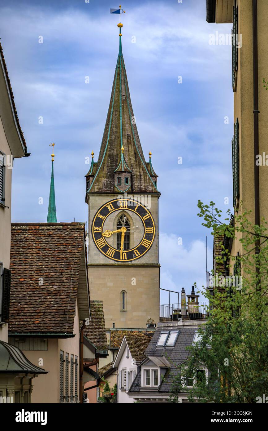 L'iconica torre dell'orologio della Chiesa di San Pietro incorniciata da edifici storici circostanti nella città vecchia o nell'Altstadt di Zurigo, Svizzera Foto Stock