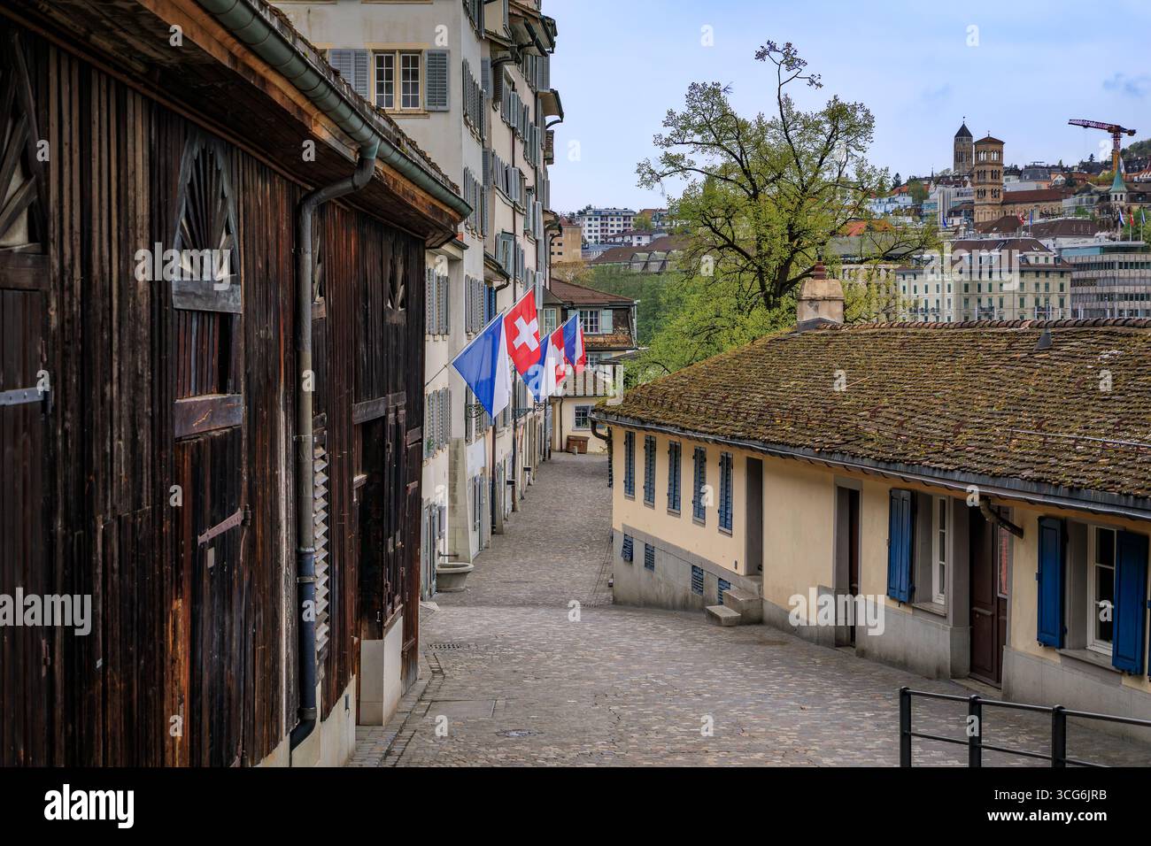 Uno stretto vicolo storico con edifici tradizionali e una vista della città sullo sfondo nel centro storico di Zurigo, Svizzera Foto Stock
