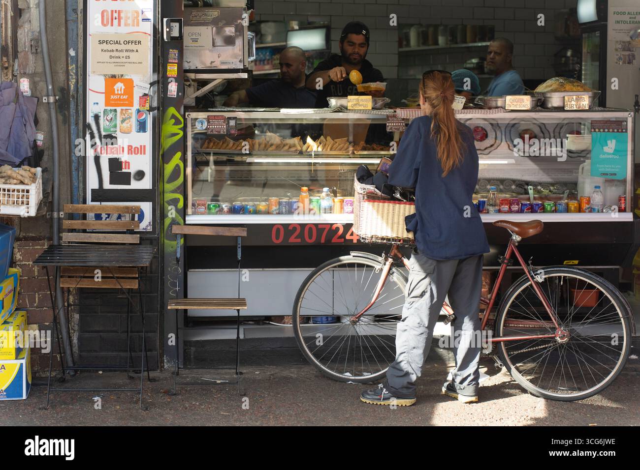 Un ciclista ordina cibo al mercato di Ridley Road a Dalston, Londra Foto Stock