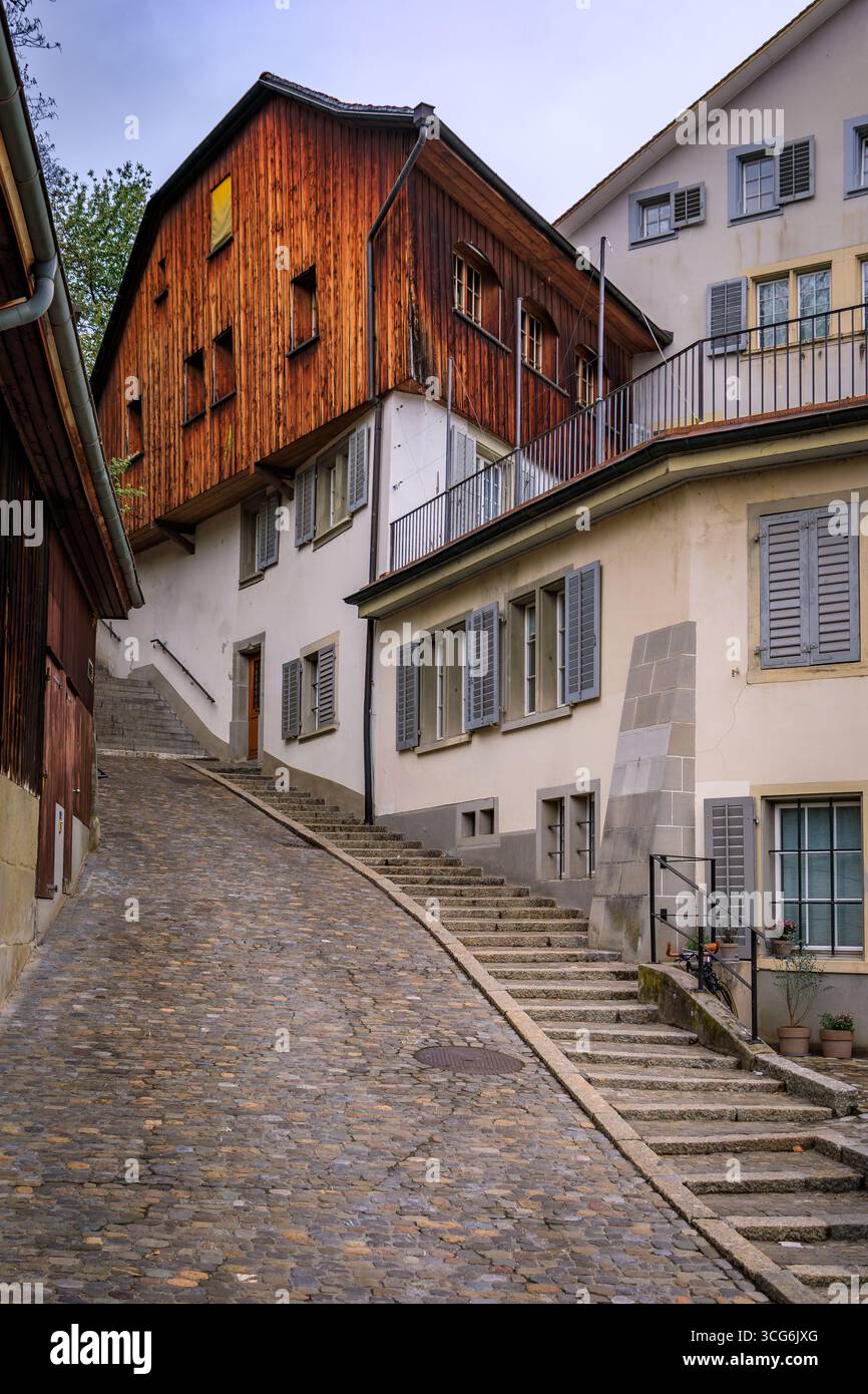 Ripida strada acciottolata nella città vecchia o nell'Altstadt di Zurigo, fiancheggiata da edifici storici caratterizzati da architettura tradizionale e facciate in legno Foto Stock