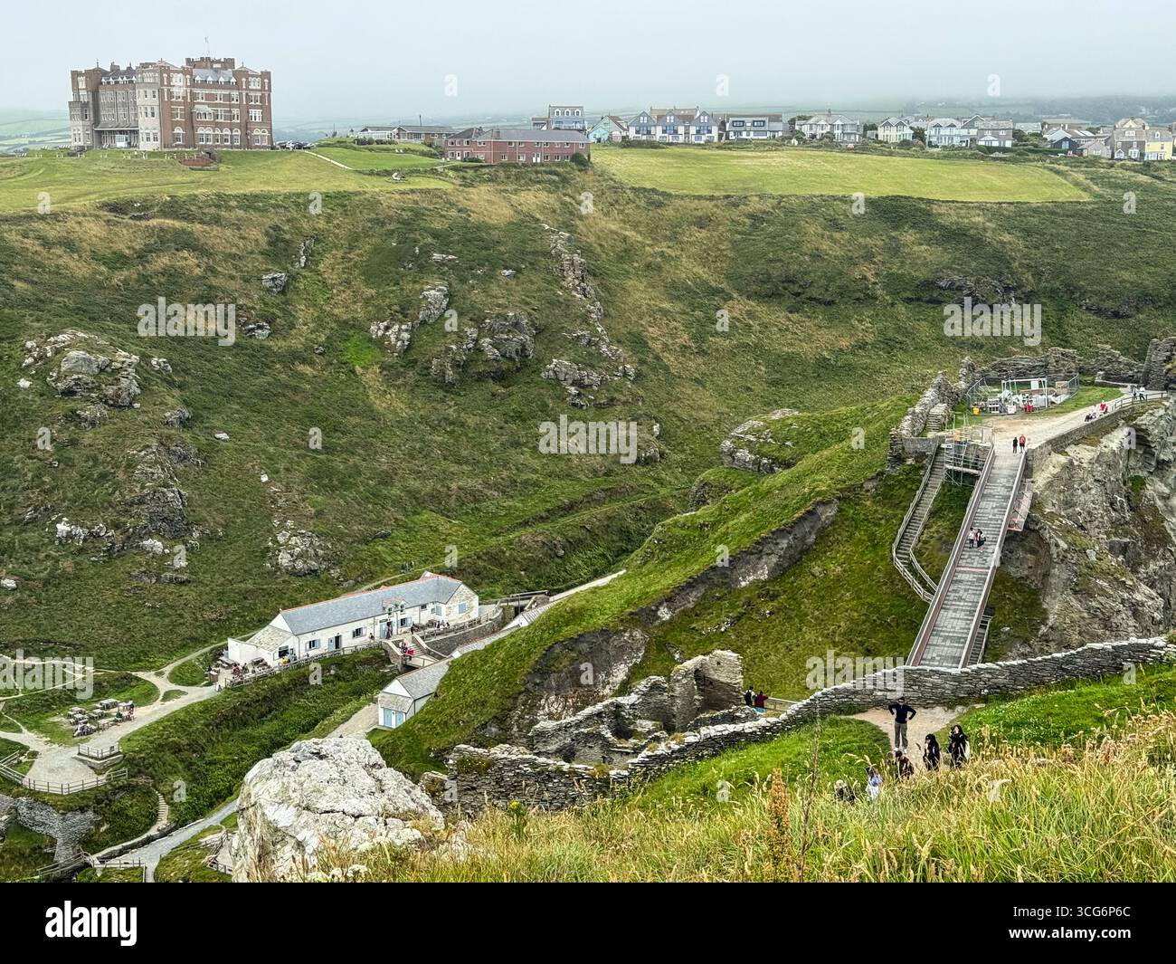 Tintagel, Cornovaglia, Inghilterra, Regno Unito Vista dalle rovine del castello di Tintagel. Camelot Castle Hotel e Tintagel Town sullo sfondo. Centro visitatori in basso a sinistra. Foto Stock