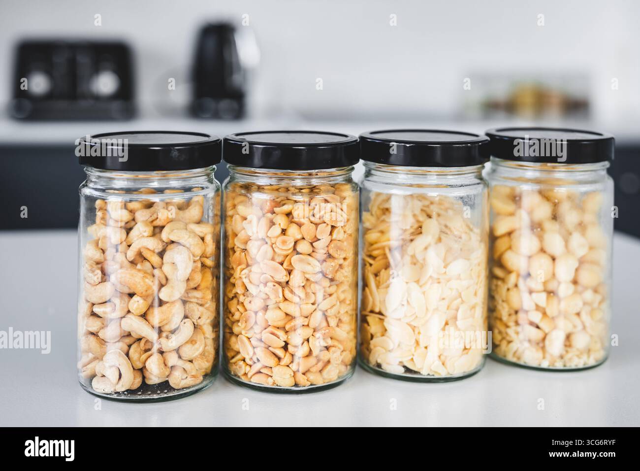 vasi di dispensa in vetro abbinati a anacardi arachidi macadamias e fiocchi di mandorle sul bancone della cucina, cibo sano e tema dispensa organizzato Foto Stock vasi di dispensa in vetro abbinati a anacardi arachidi macadamias e fiocchi di mandorle sul bancone della cucina, cibo sano e tema dispensa organizzato Foto Stock