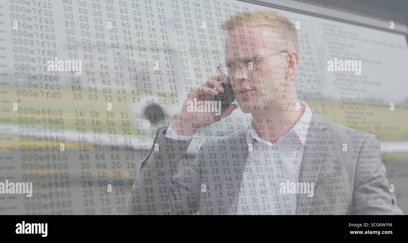 Uomo in tuta grigia che parla con lo smartphone in ufficio, con microfono da scrivania, sovrapposizione codice, spazio di copia Foto Stock