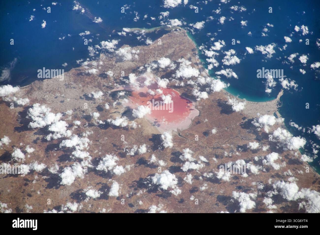 Sebkha di Moknine in Tunisia. Le nuvole si aggirano lungo la costa tunisina mentre la stazione spaziale Internazionale si innalza a 260 km di altezza. Vicino alla vetta centrale, dove la costa incontra il Mar Mediterraneo, è visibile il lago salato rosa di Sebkha di Moknine. Con poco afflusso da fiumi e torrenti, il lago è alimentato da piogge che sfociano colori vivaci nel bacino, lasciando dietro i resti di una "salina", la crosta bianca di sale e minerali che confinano con l'acqua. 7 ottobre 2023 una versione ottimizzata di un'immagine originale della NASA: Credit NASA Foto Stock