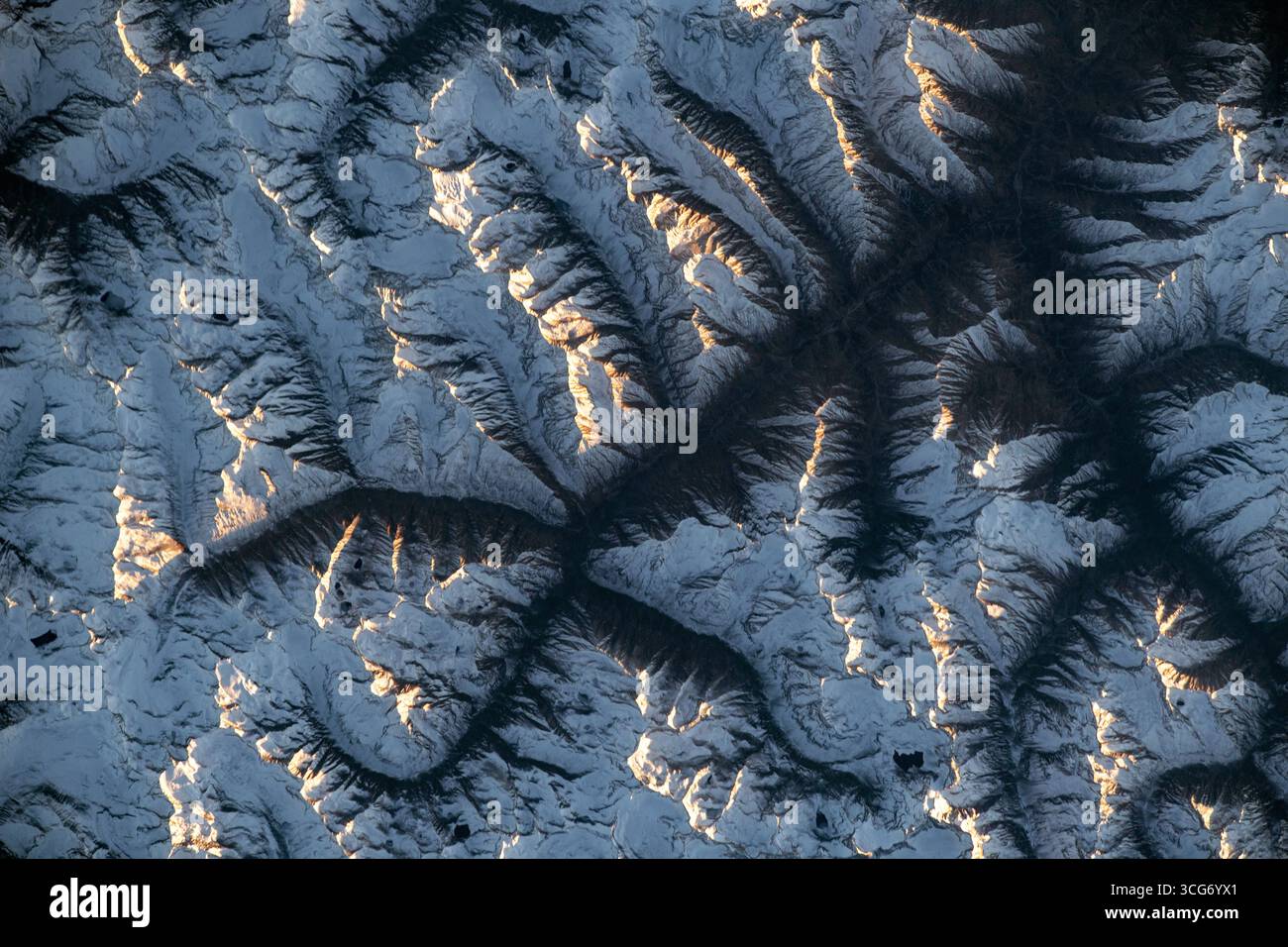 La catena montuosa Hindu Kush, Pakistan. Quello che sembra la diffusione delle radici è una vista della catena montuosa di Hindu Kush dalla stazione spaziale Internazionale, che si innalza a 260 miglia sopra. La base delle montagne è ombreggiata dal Sole che si riflette sulle vette. Estendendosi attraverso l'Asia centrale e meridionale, la catena si estende per 500 miglia (800 km). 20 novembre 2023 una versione ottimizzata di un'immagine originale della NASA: Credit: NASA/LOHara Foto Stock