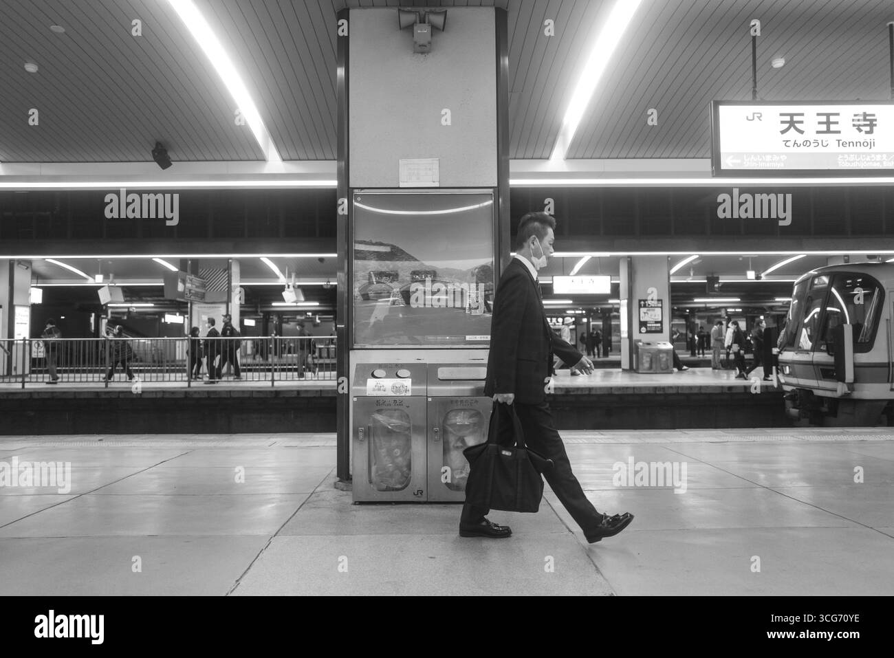 Un professionista d'affari passeggia attraverso la stazione di Tenno ji in una prospettiva dinamica monocromatica, enfatizzando i movimenti e le complessità dei pendolari urbani, Tennoj Foto Stock