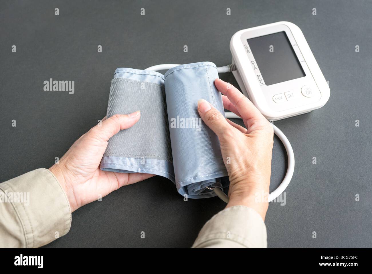 Donna che raggiunge il dispositivo di monitoraggio della pressione sanguigna. Vista ravvicinata. Foto Stock