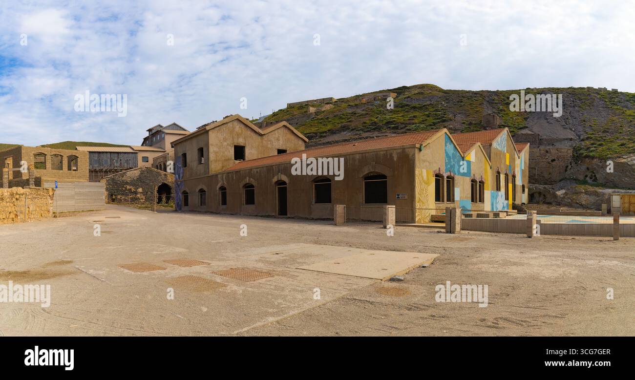 Antico complesso minerario di piombo, argento e zinco ad Argentiera, in Sardegna, con edifici intemprati e pittoreschi murali in un aspro paesaggio collinare. Foto Stock
