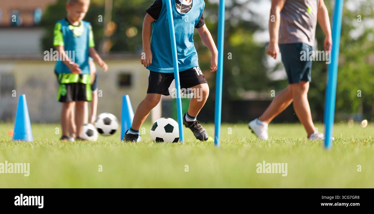 Trapani da allenamento calcio per bambini con coni e pali. Allenamento giovanile di calcio, abilità di dribbling ed esercizi di controllo palla su Grass Field Foto Stock