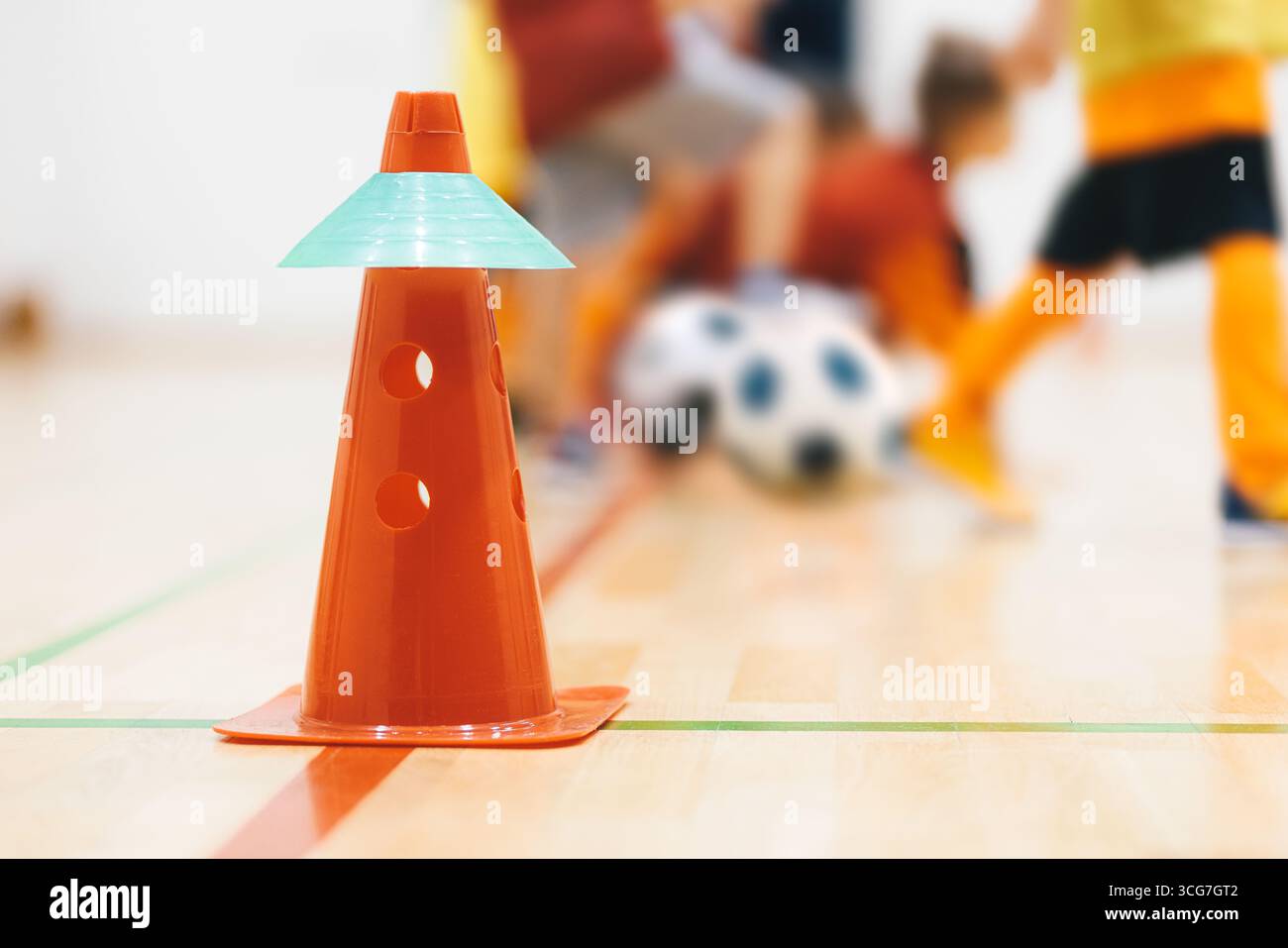 Allenamento di calcio al coperto per bambini con coni. Allenamenti giovanili di calcio, controllo palla e esercizi di agilità per bambini sul piano del palazzetto dello sport Foto Stock