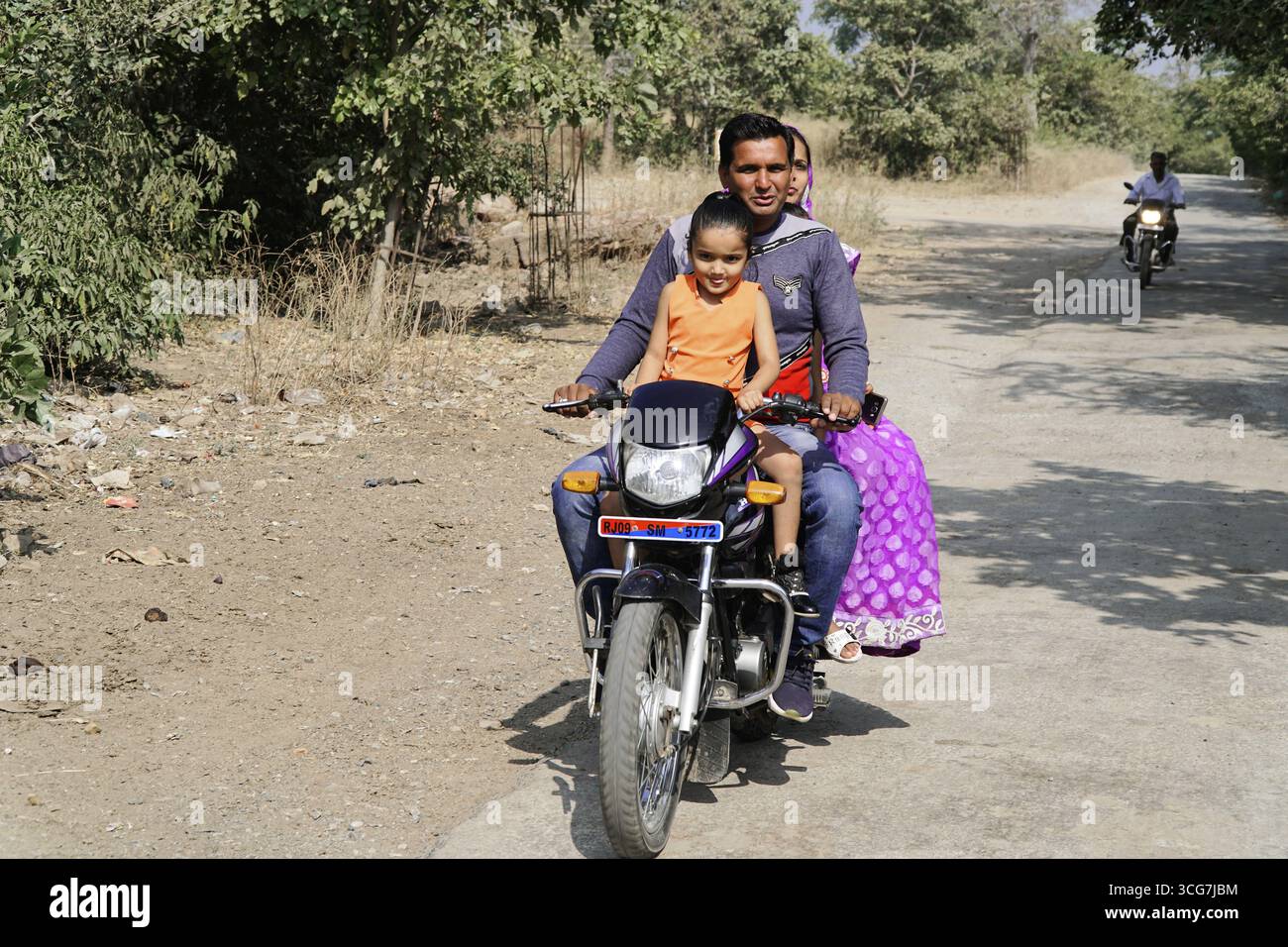 Kota, Rajasthan, India del Nord, Asia, famiglia in moto lungo una strada rurale con il sole, India Foto Stock