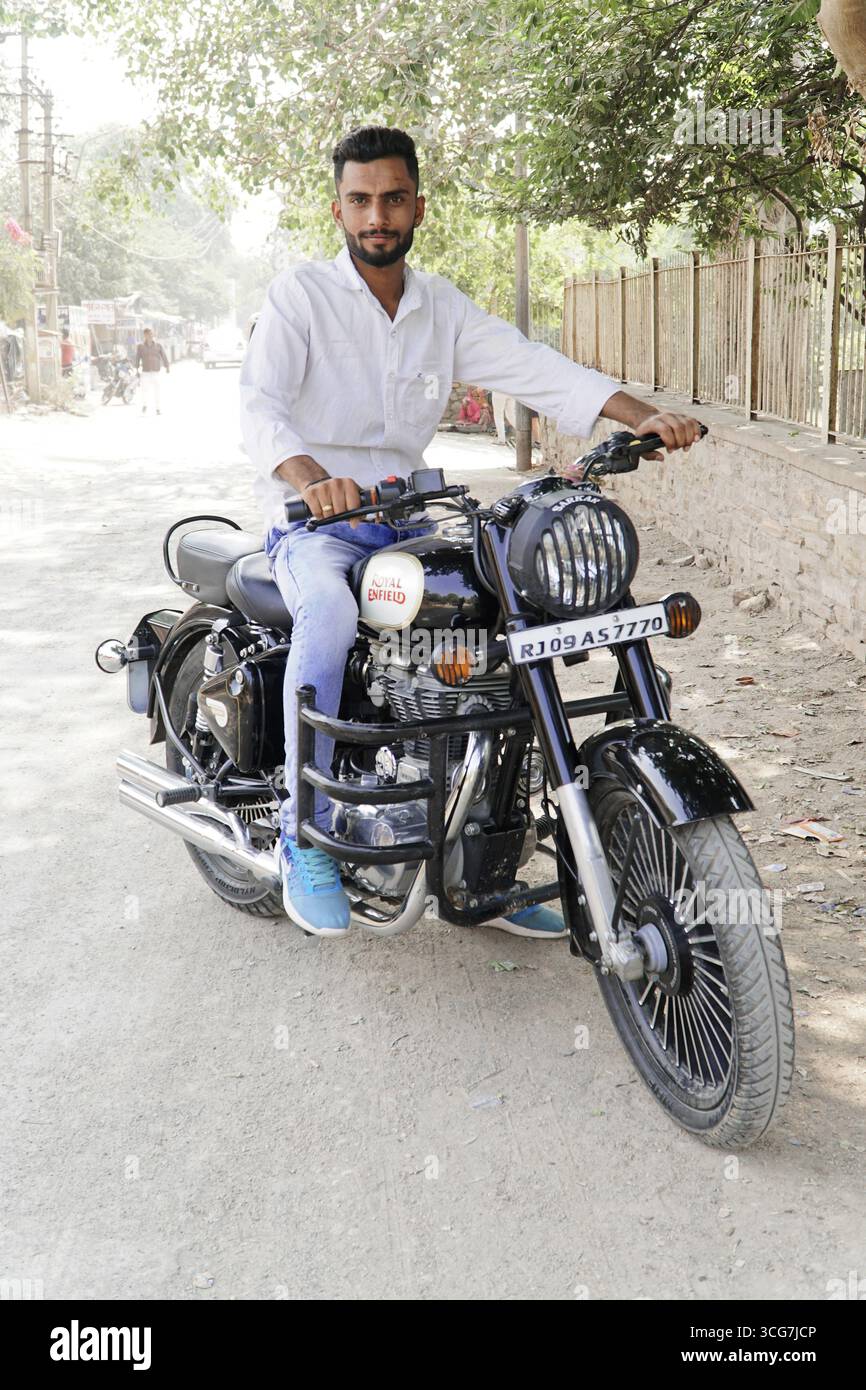 Kota, Rajasthan, India del Nord, Asia, uomo seduto su una moto nera Royal Enfield su una strada polverosa, India Foto Stock