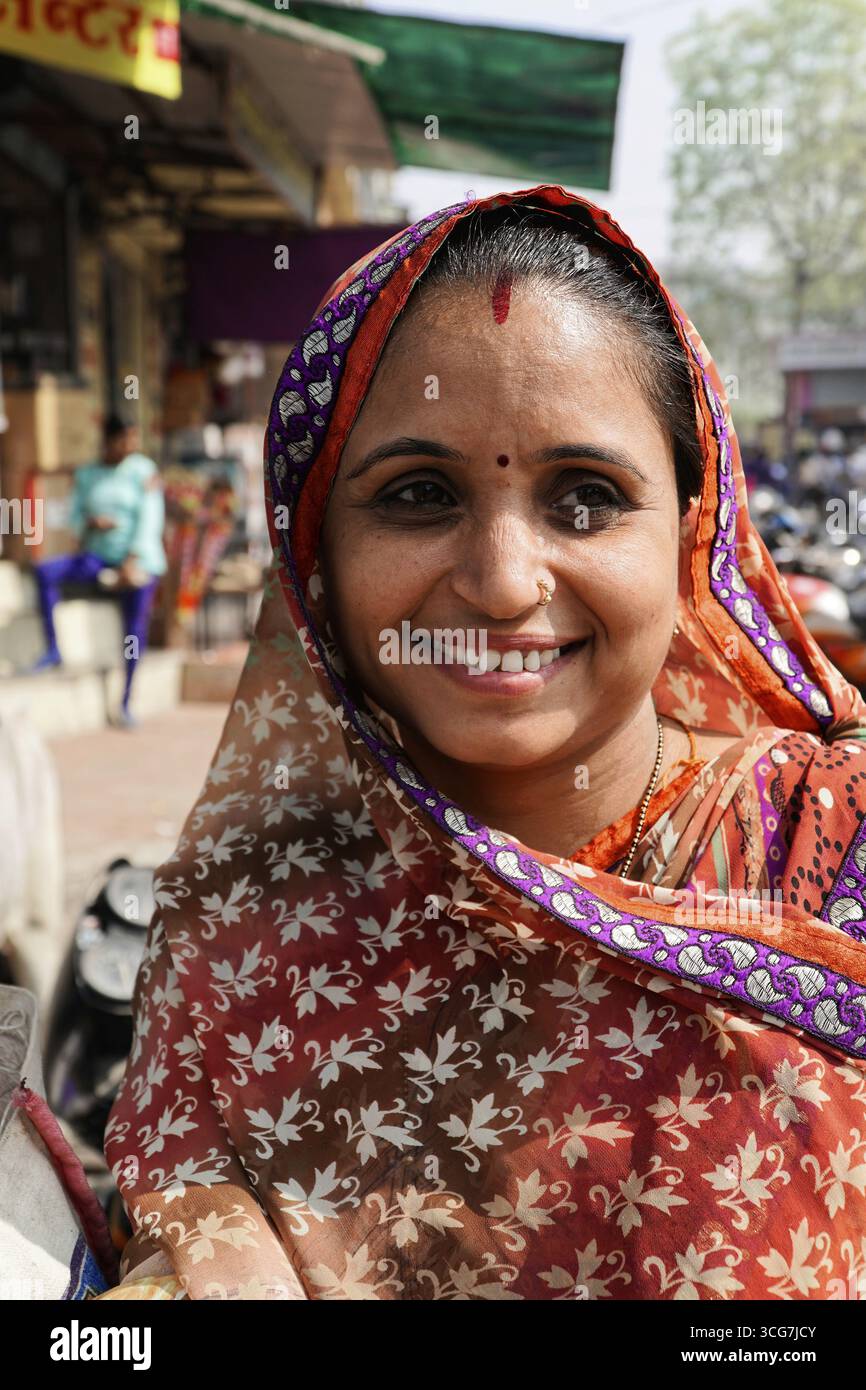 Kota, Rajasthan, India del Nord, Asia, donna sorridente nel tradizionale sari indiano di fronte a una strada trafficata, l'India Foto Stock