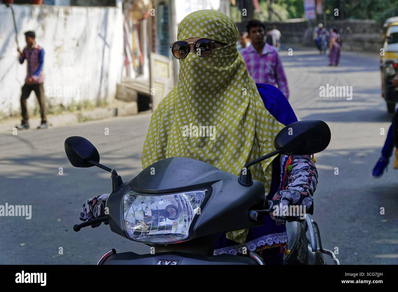 Udaipur, Rajasthan, India settentrionale, India, Asia, una donna velata con occhiali da sole cavalca una moto su una strada trafficata Foto Stock