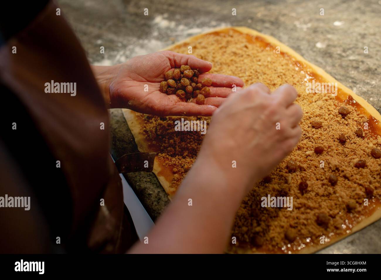Particolare della preparazione della Gubana, una tipica torta friulana, con aggiunta di uva sultanina al ricco ripieno di frutta secca. Una pasticceria artigianale. Foto Stock