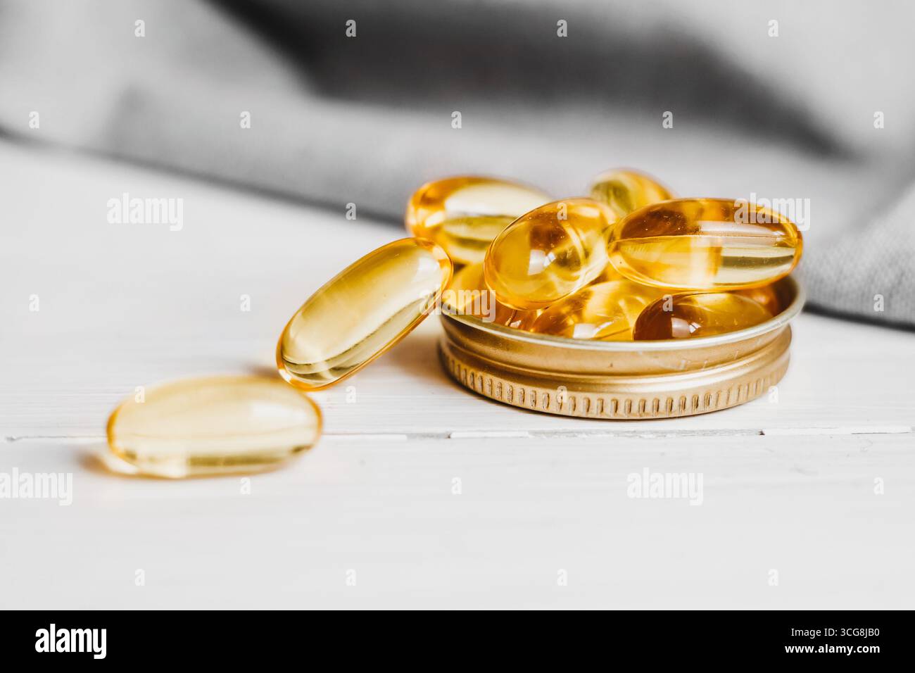 Capsule gialle, compresse, pillole di olio di pesce gialle gialle girate su un tavolo di legno bianco. Omega complesso vitaminico 3,6,9. Foto Stock