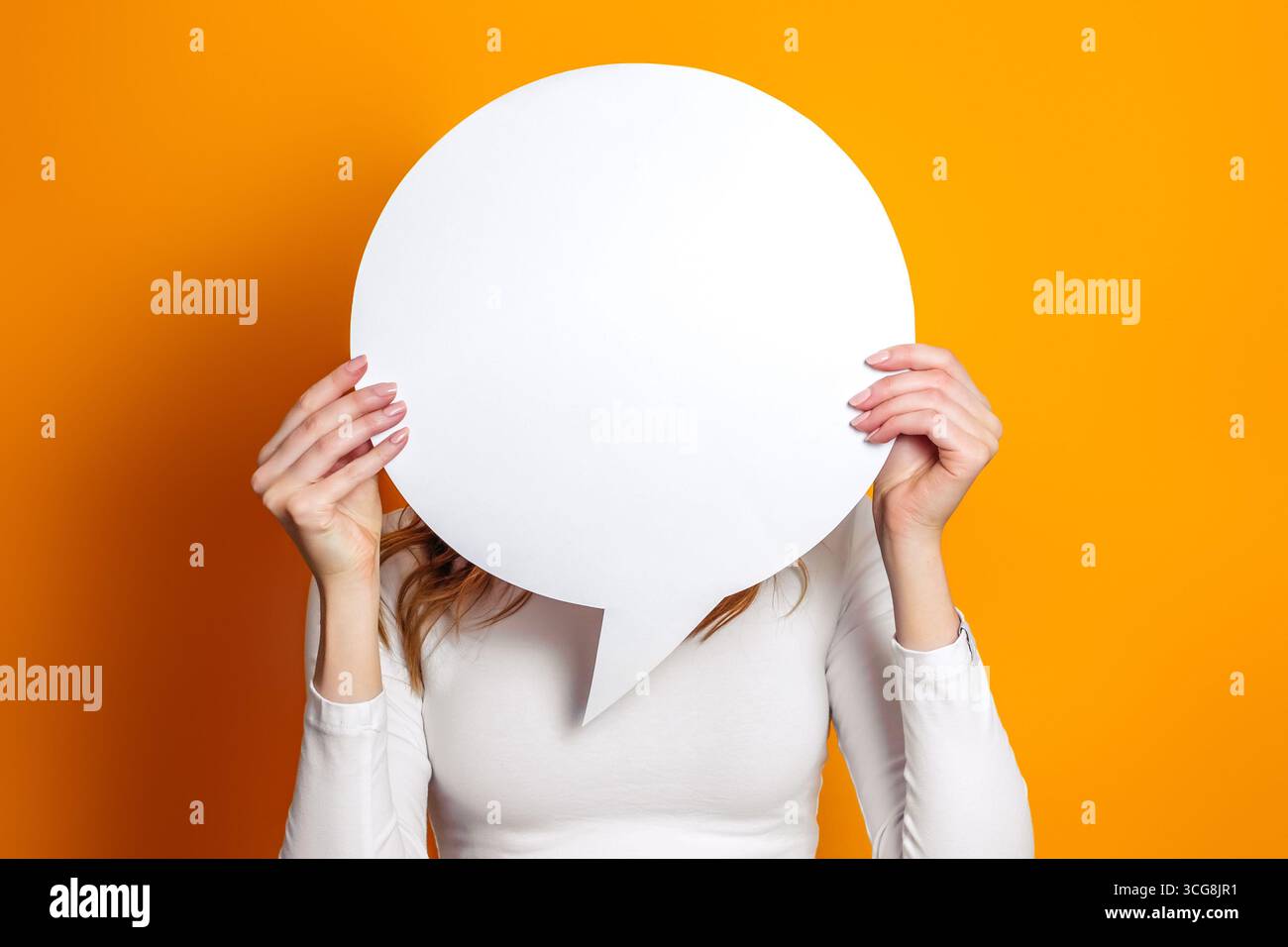 Lo studente tiene un palloncino bianco vuoto isolato su uno sfondo arancione dello studio. copia spazio Foto Stock