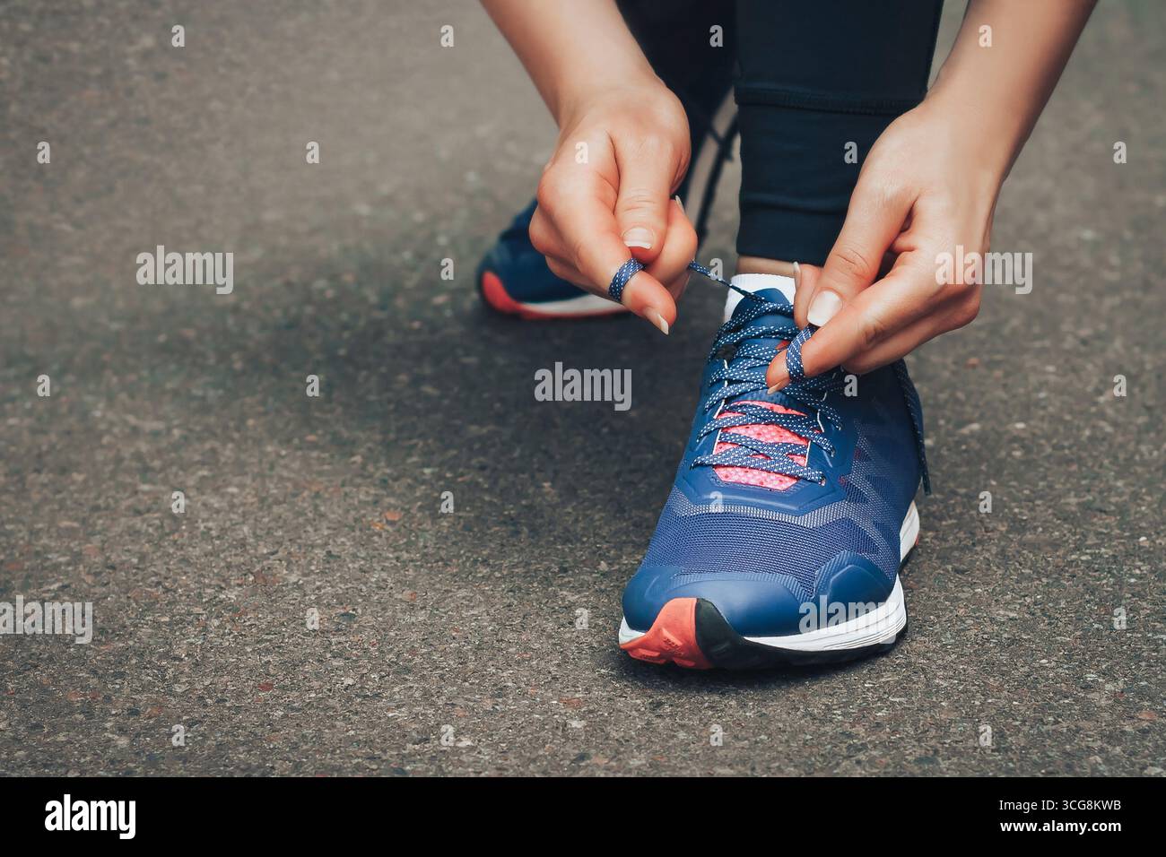 Corsa serale. Giovane donna che corre su una strada rurale durante il tramonto con le sneakers blu. Ragazza che lega le scarpe prima di correre Foto Stock