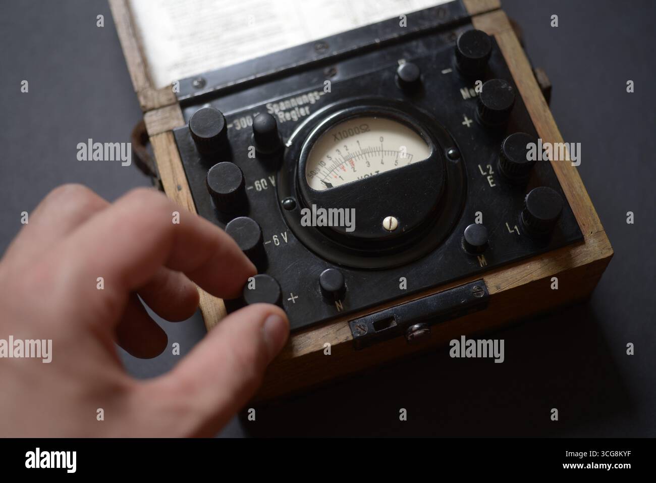 Voltmetro analogico vintage in una custodia in legno con calibro ad ago circolare e manopole multiple, azionabile a mano. Foto Stock