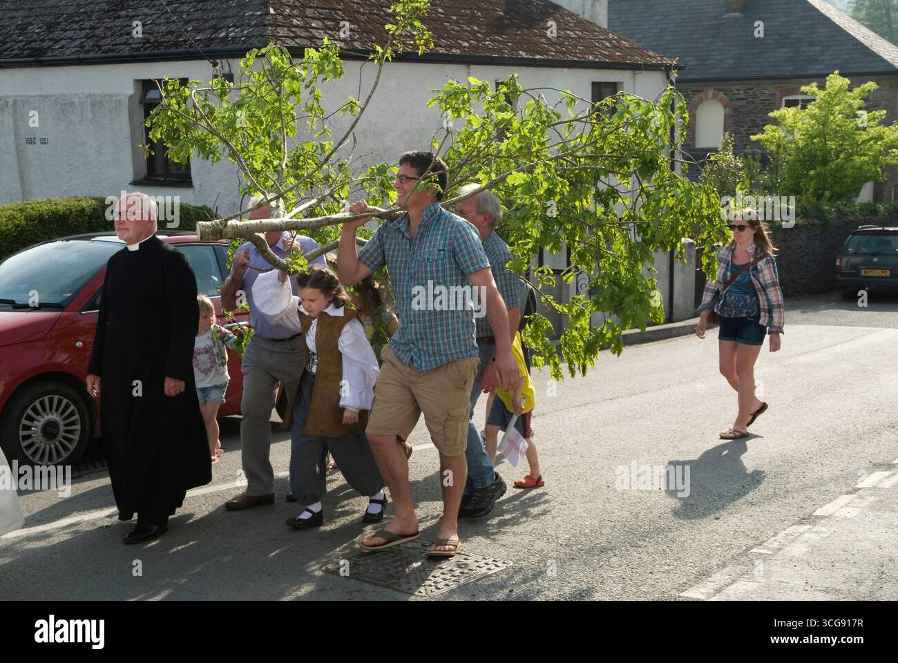 Oak Apple Day 29 maggio Cornovaglia. Un ramo di legno di quercia viene trasportato attraverso il villaggio guidato dal Revd. Phillip Biggs fino alla chiesa di St. Neot, dove viene issata in cima alla torre della chiesa. Noto anche come Royal Oak o Restoration Day 29 of May è la celebrazione del restauro di re Carlo II al trono di Inghilterra, Scozia e Irlanda nel 1651. St Neot, Cornovaglia anni '2016 2010, Regno Unito, HOMER SYKES Foto Stock