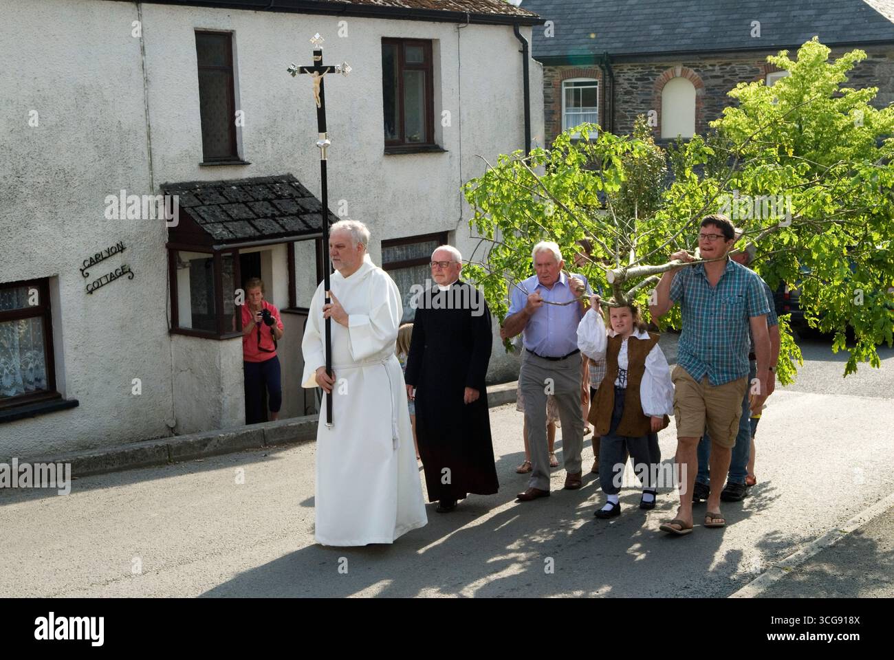 Oak Apple Day 29 maggio Cornovaglia. Un ramo di legno di quercia viene trasportato attraverso il villaggio guidato dal Revd. Phillip Biggs fino alla chiesa di St. Neot, dove viene issata in cima alla torre della chiesa. Noto anche come Royal Oak o Restoration Day 29 of May è la celebrazione del restauro di re Carlo II al trono di Inghilterra, Scozia e Irlanda nel 1651. St Neot, Cornovaglia anni '2016 2010, Regno Unito, HOMER SYKES Foto Stock