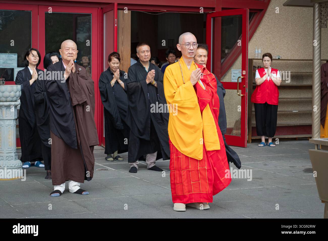 Guidati dal loro abate, monaci e suore buddisti lasciano il tempio per bruciare denaro fantasma che onora e benedice i defunti nell'aldilà Foto Stock