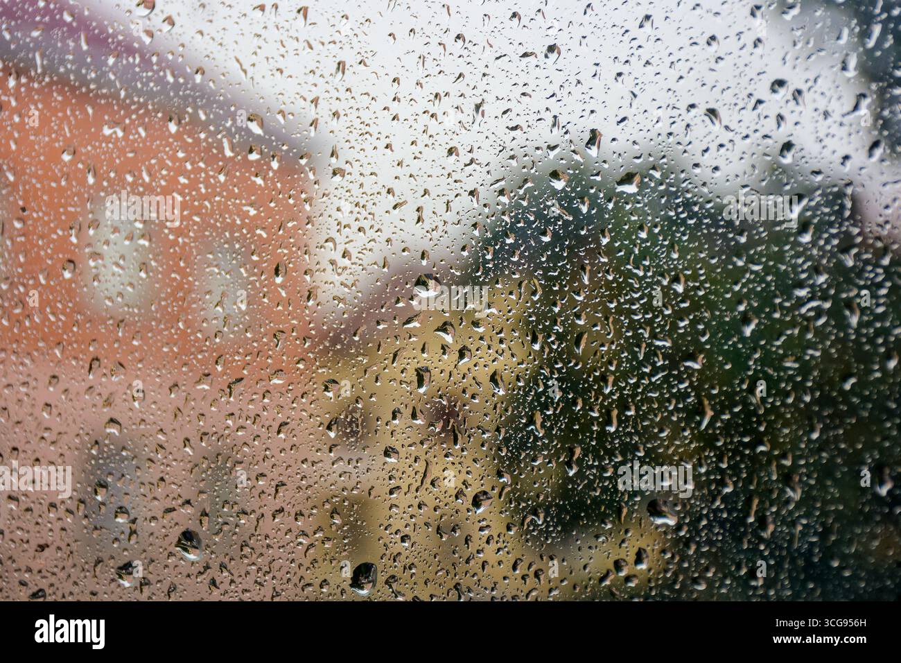 sfondo finestra bagnato. goccia di pioggia sulla superficie del vetro. concetto di maltempo. il paesaggio urbano è sfocato in lontananza Foto Stock