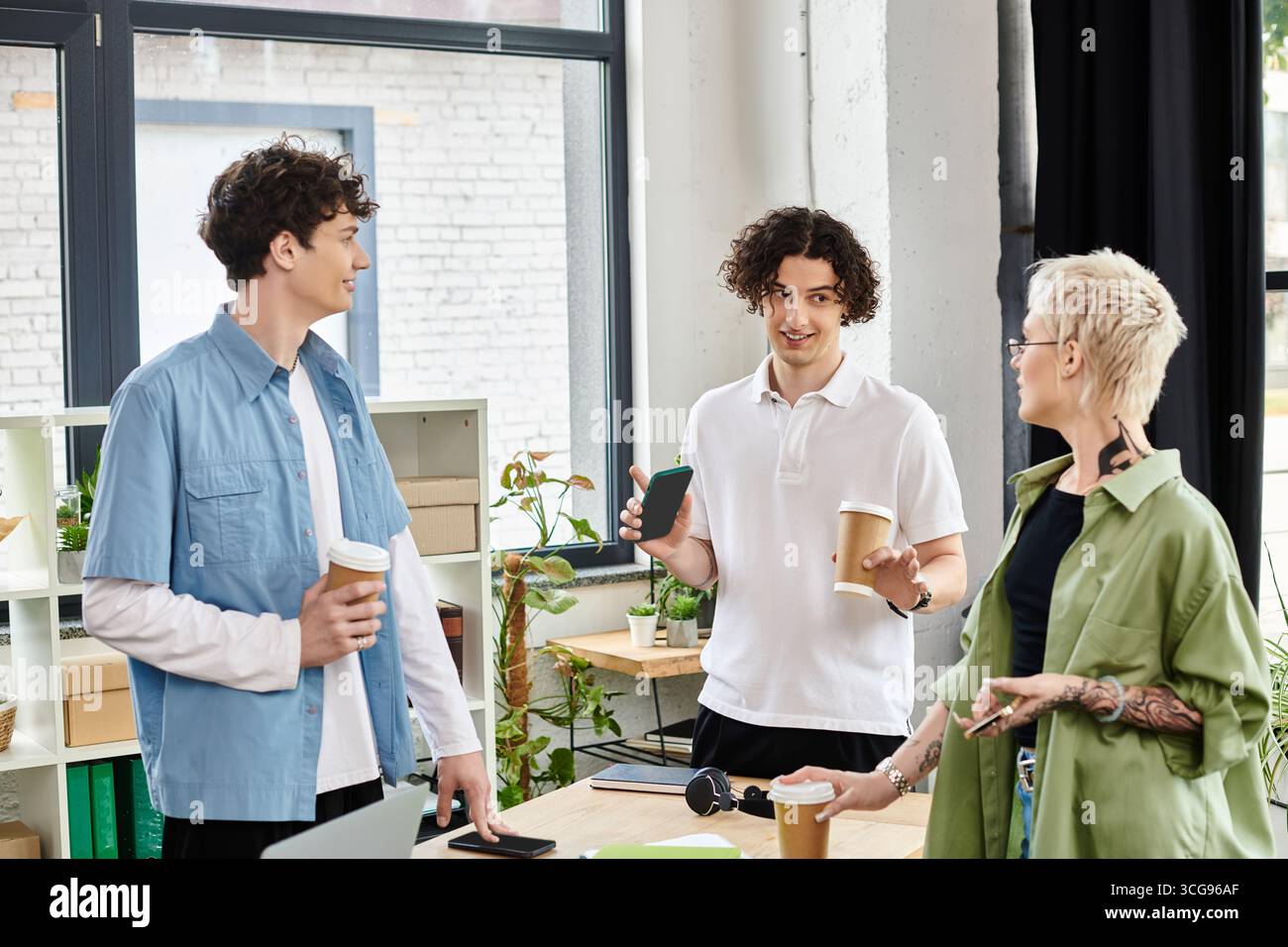 Giovani energici collaborano con un caffè in un ufficio moderno pieno di verde. Foto Stock