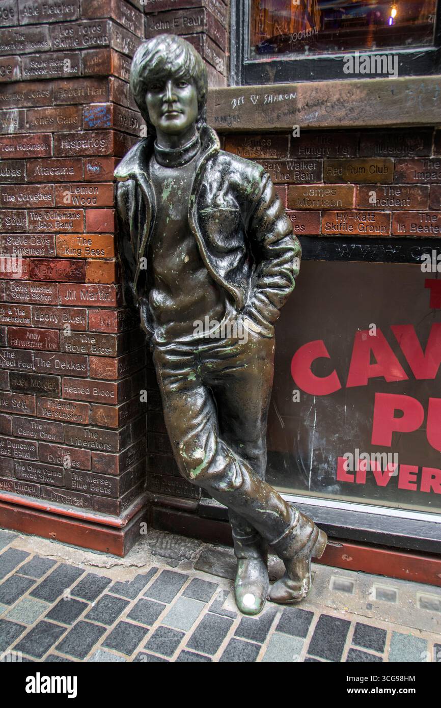 La statua di John Lennon più giovane si è esposta contro il Cavern Wall of Fame, di fronte al Cavern Pub Foto Stock