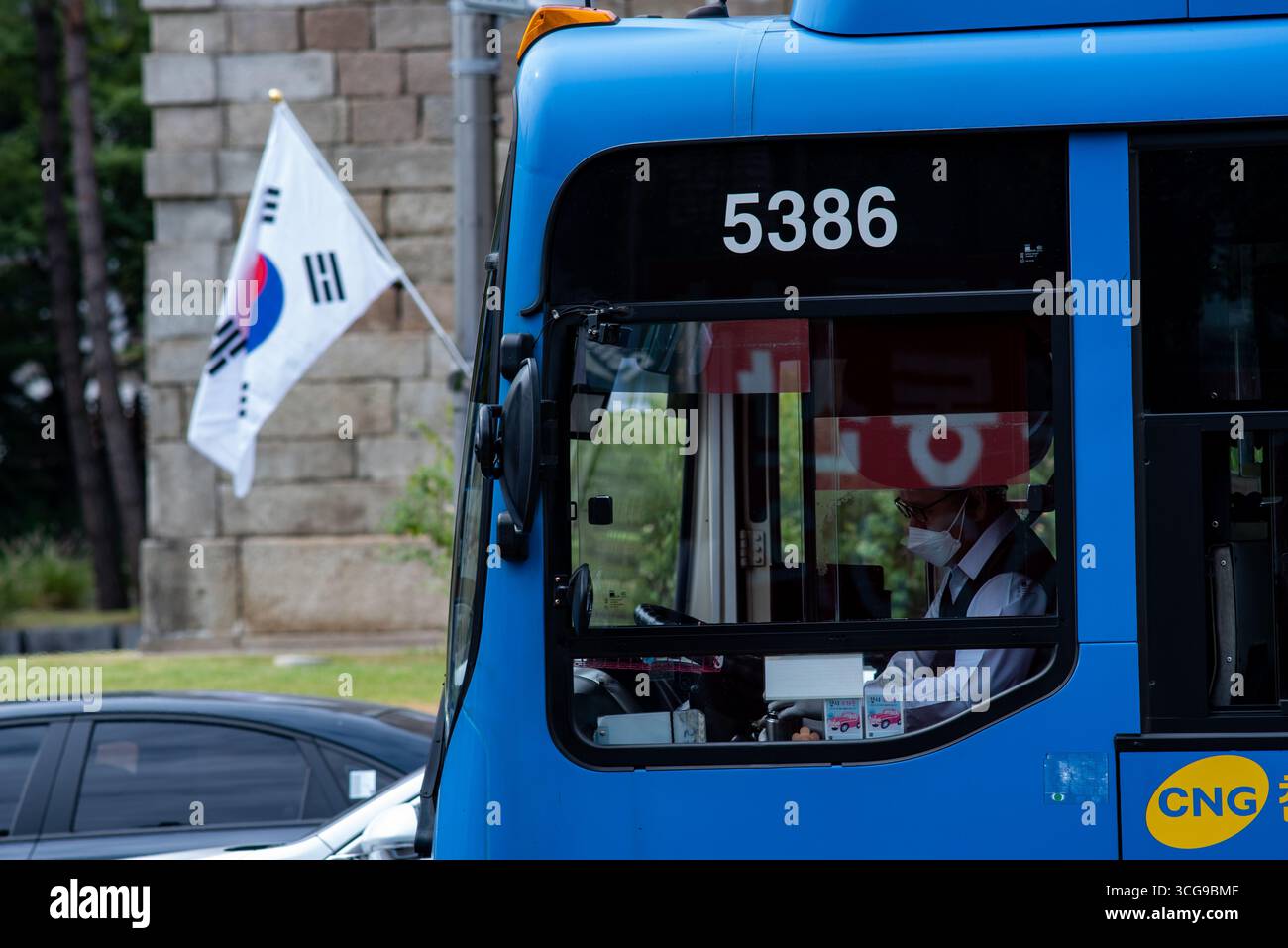 Autobus pubblico con il numero 5386, con autista che indossa una maschera, e una bandiera sudcoreana sullo sfondo a Seoul, Corea del Sud, il 19 settembre 2021 Foto Stock