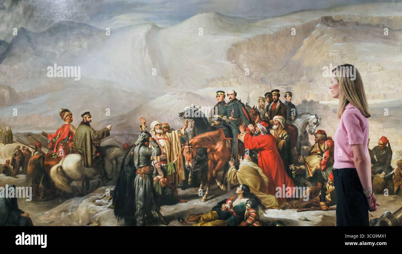 Londra, Regno Unito. 27 agosto 2025. Personale del museo con "la capitolazione di Kars, 28 novembre 1855" (1857) di Thomas Jones Barker, un'opera in questa mostra. Il National Army Museum ha commissionato ad artisti contemporanei di reinterpretare iconici dipinti militari vittoriani nella mostra "Myth and Reality: Military Art in the Age of Queen Victoria" presso il museo. Crediti: Imageplotter/Alamy Live News Foto Stock
