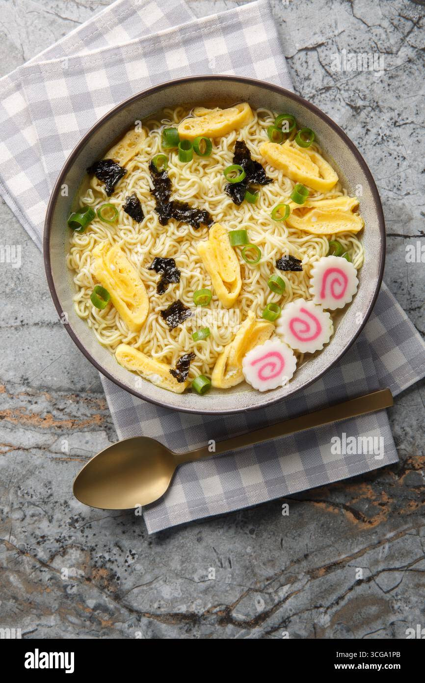 Zuppa di noodle hawaiana Saimin con nori, omelette, kamaboko e cipolle verdi in primo piano nel piatto sul tavolo. Vista dall'alto verticale Foto Stock