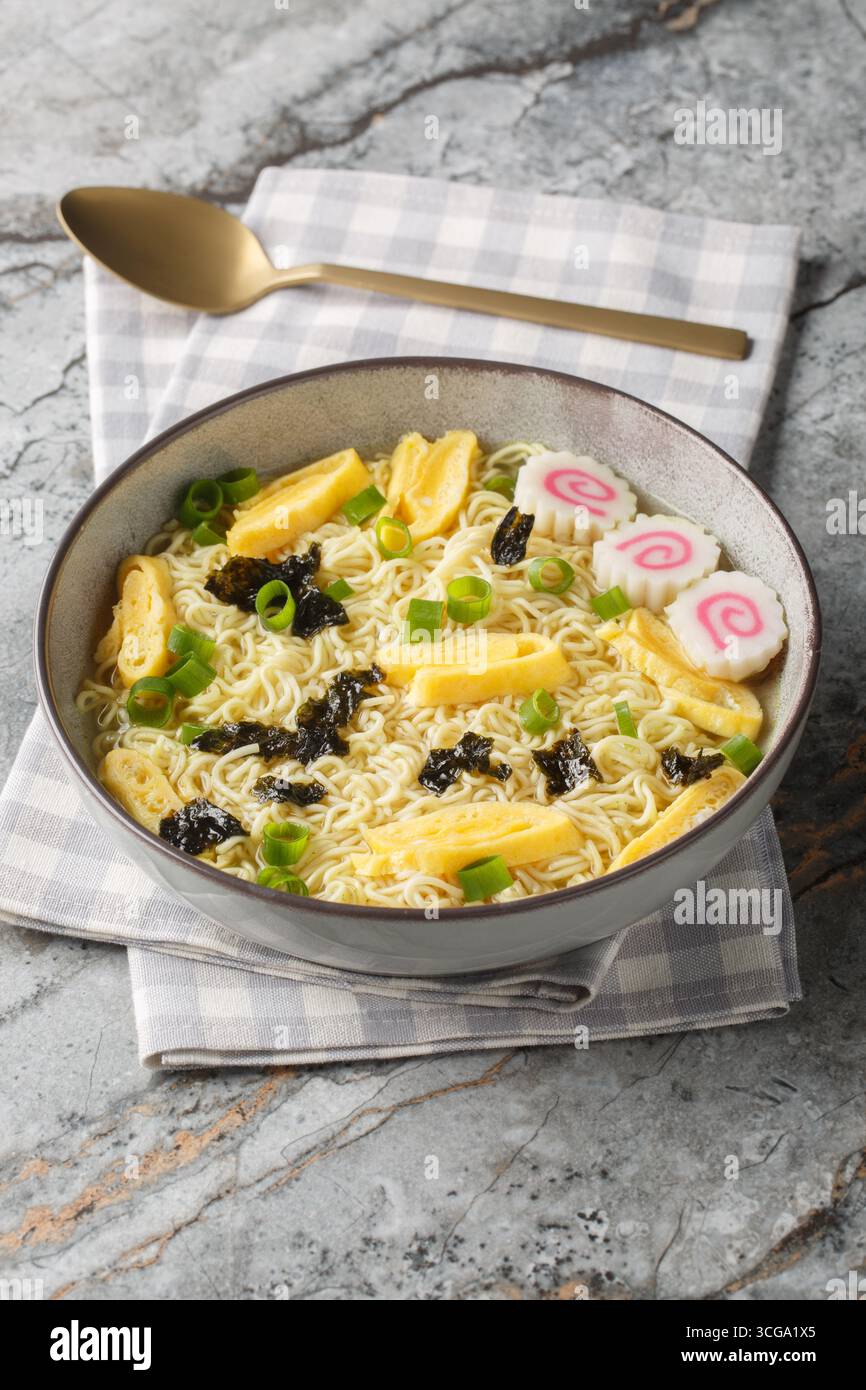 Zuppa di noodle hawaiana Saimin con nori, omelette, kamaboko e cipolle verdi in primo piano nel piatto sul tavolo. Orizzontale Foto Stock