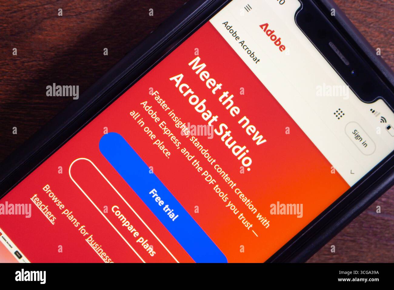 Primo piano di uno smartphone che visualizza la pagina introduttiva di Adobe Acrobat Studio con strumenti per la creazione di contenuti, offerte di prova e piani. Foto Stock