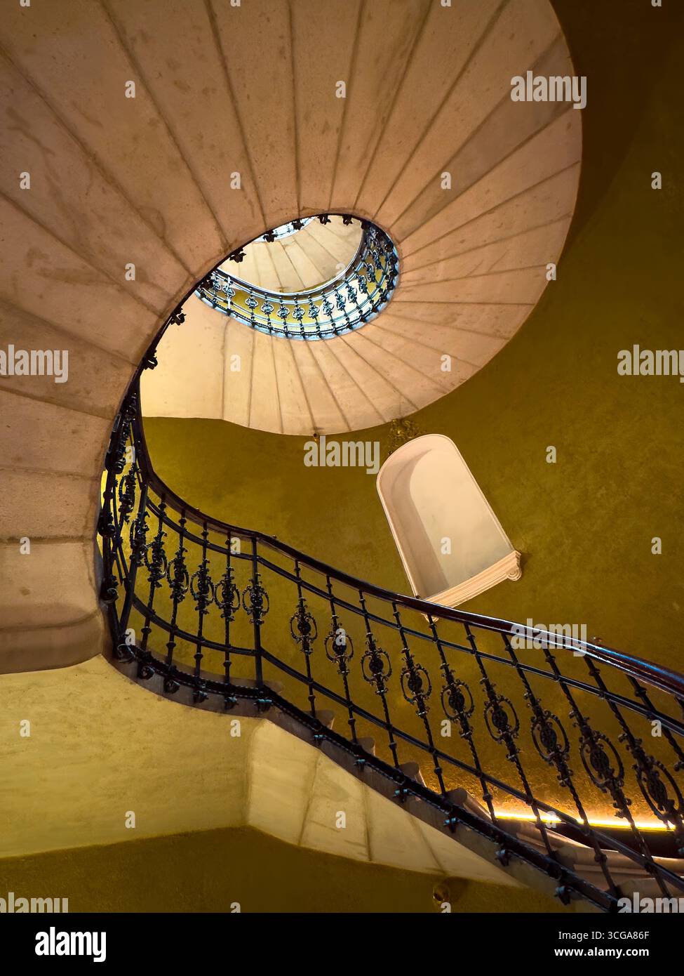 Elegante scala a chiocciola circondata da pareti dorate con ringhiere in ferro ornate viste dall'alto. Foto Stock