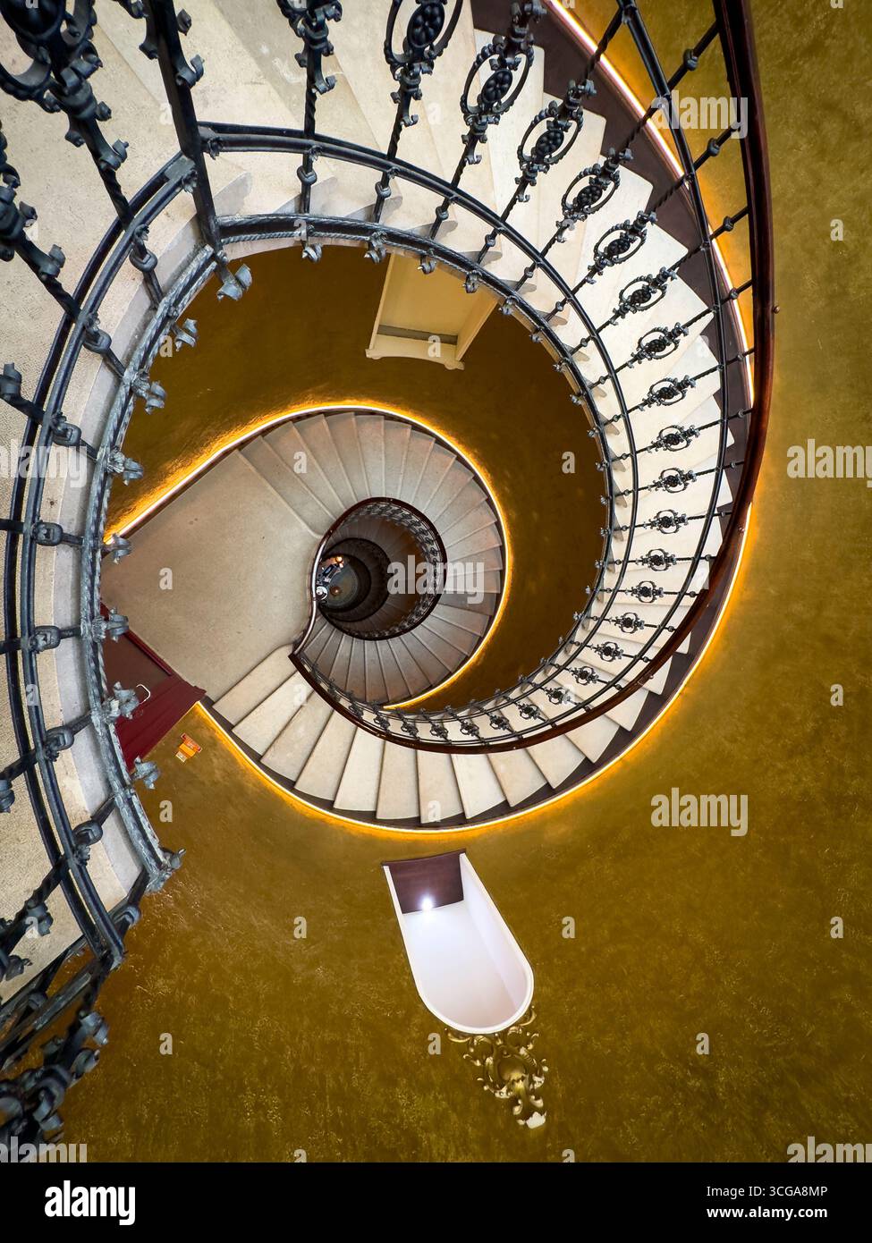 Elegante scala a chiocciola circondata da pareti dorate con ringhiere in ferro ornate viste dall'alto. Foto Stock