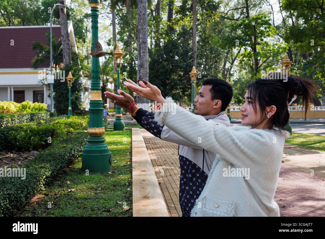 Una giovane coppia libera un uccello in cattività (la tradizione buddista del fangsheng), Royal Resident Garden, Siem Reap, Cambogia Foto Stock