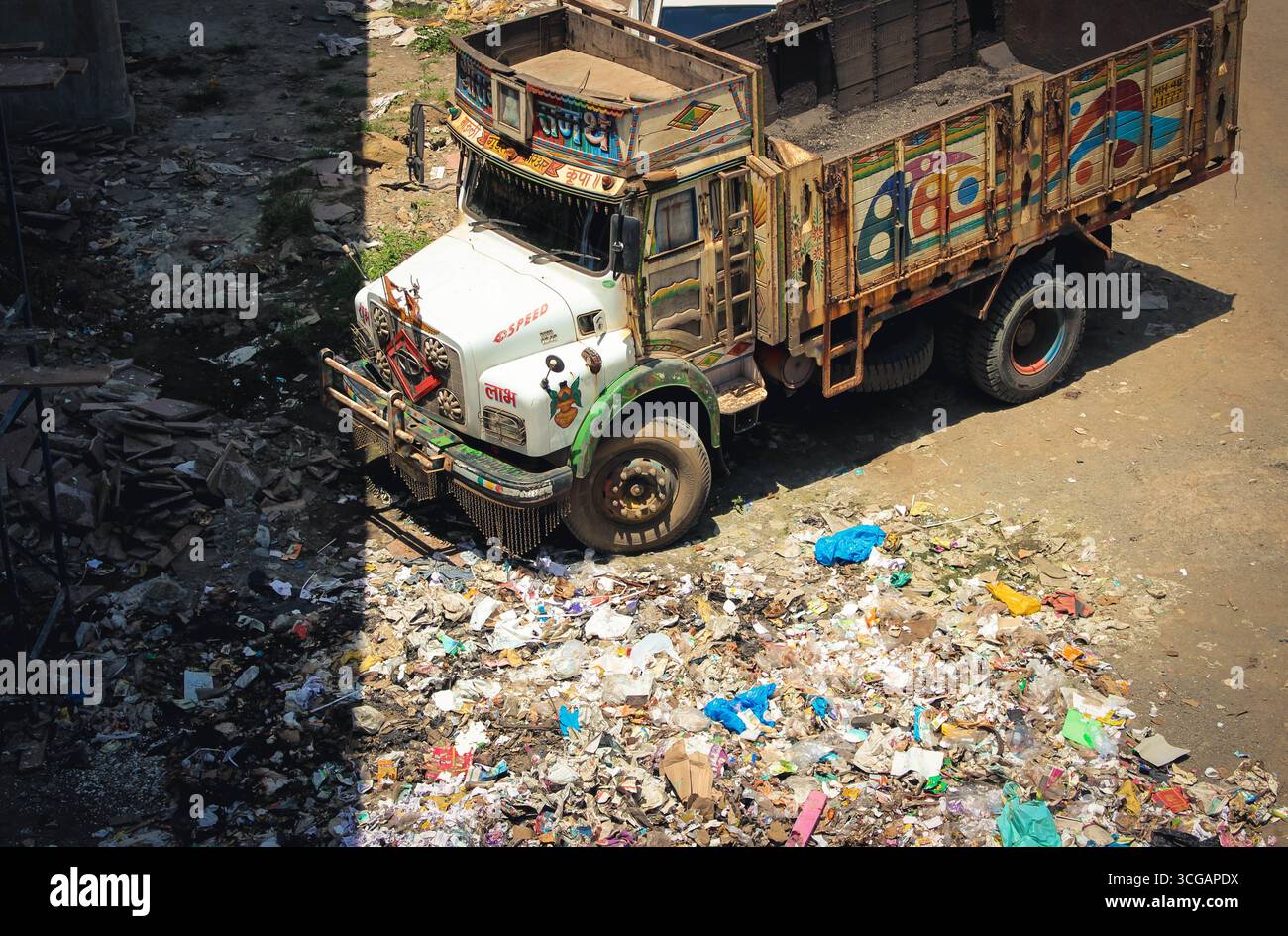 Un camion parcheggiato in strade indiane disseminate di rifiuti, raffigurante sfide per i rifiuti urbani, strade disordinate e problemi ambientali in città affollate Foto Stock