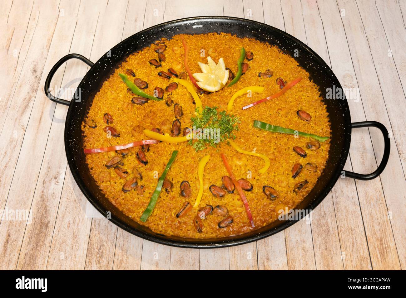 Paella di pesce bianco con rana e nasello, cotta con brodo fatto in casa che permea ogni chicco di riso Foto Stock