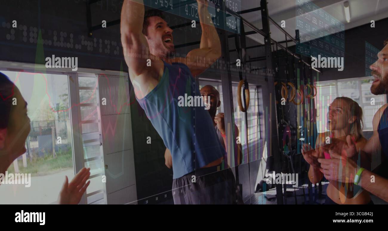 Uomo muscoloso in camicia senza maniche blu che esegue pull-up sul bar in palestra, con compagni di tifo Foto Stock
