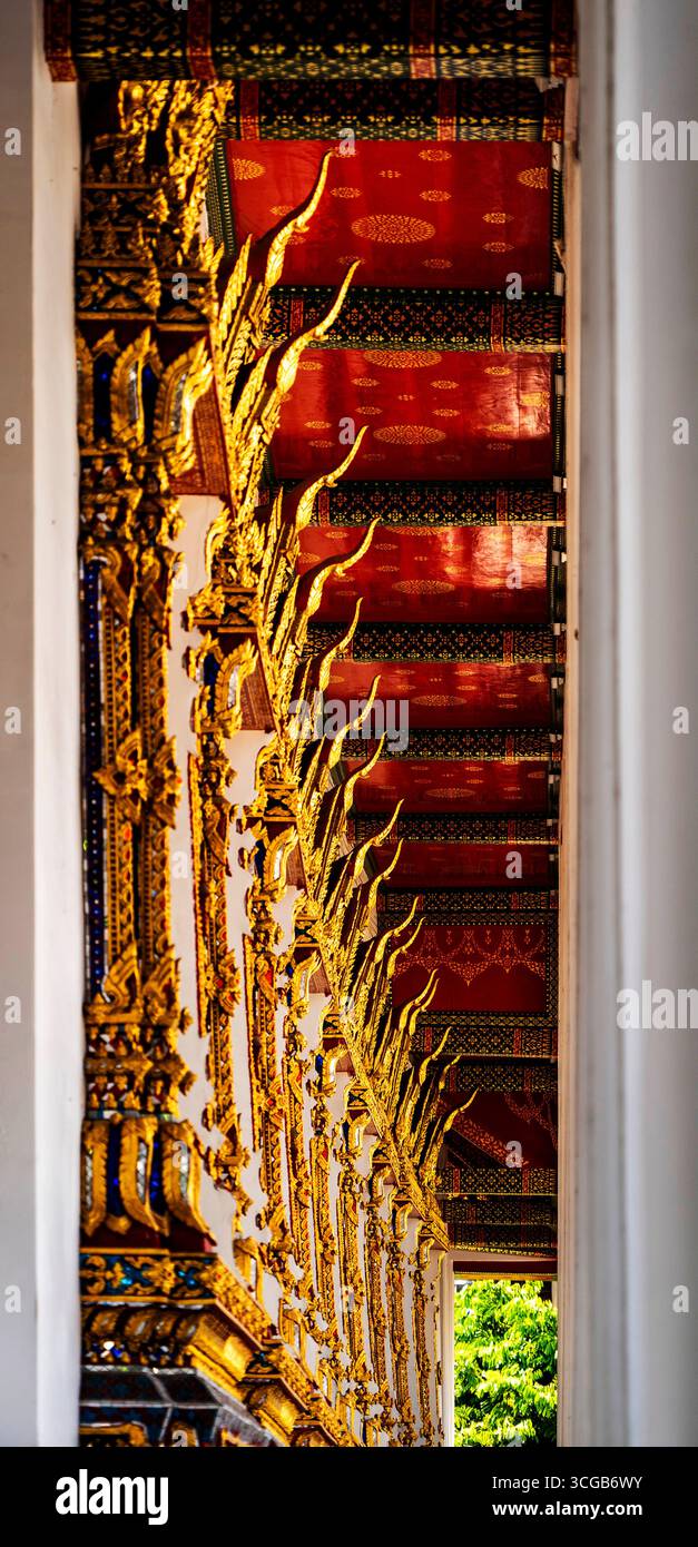 Intricati dettagli architettonici di un tempio con decorazioni dorate ornate e un vivace soffitto rosso Foto Stock