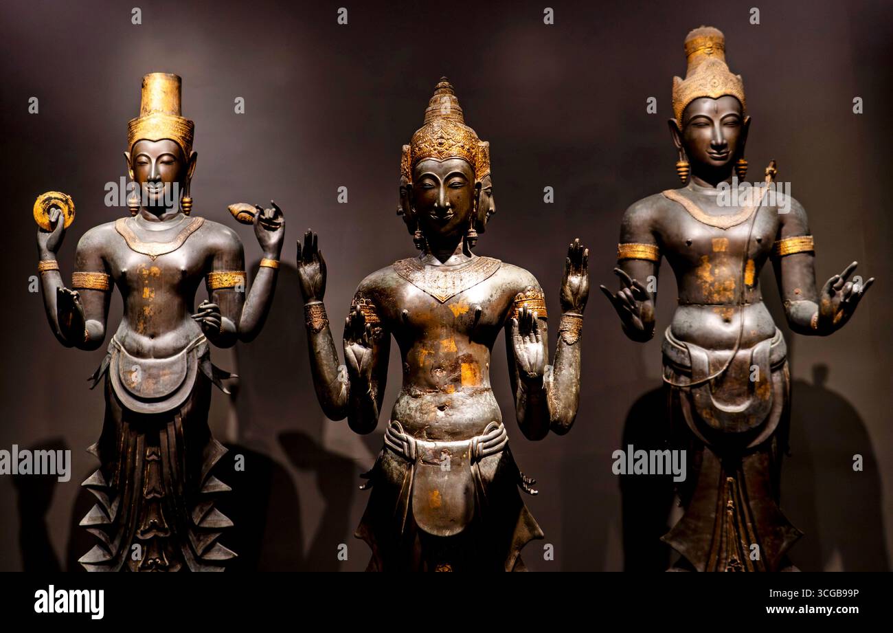 Tre antiche statue in bronzo di divinità, che mostrano dettagli intricati e abbigliamento tradizionale, su sfondo scuro Foto Stock