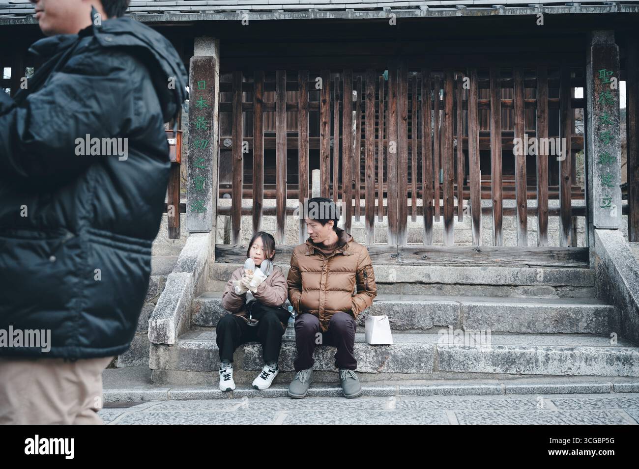 Padre e figlia si godranno un dolce sui gradini di pietra di un cancello del tempio in legno nel quartiere di Higashiyama a Kyoto Foto Stock