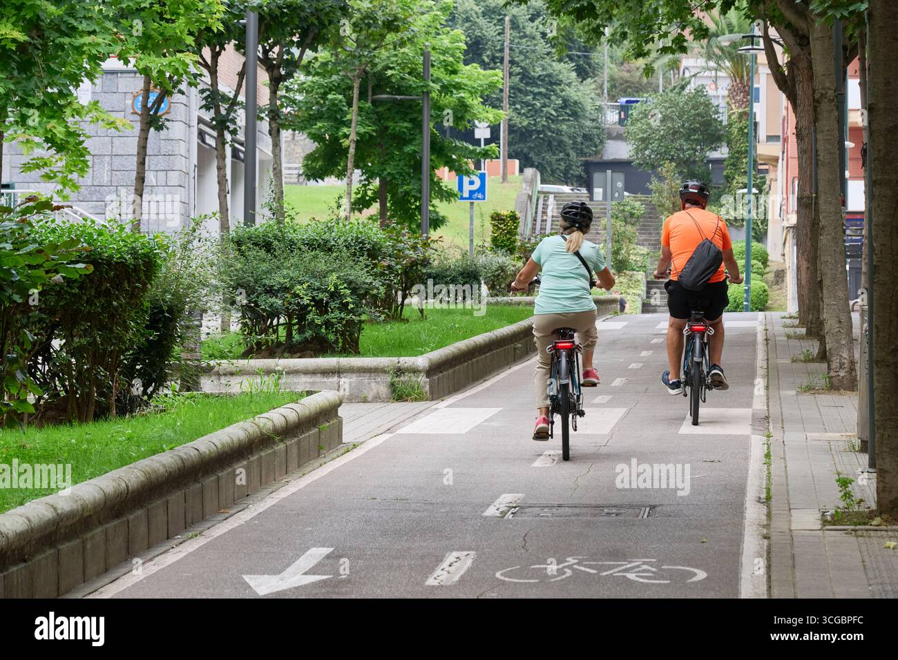 Coppie anziane che si godono una piacevole corsa sulle loro biciclette elettriche lungo una pista ciclabile dedicata, promuovendo uno stile di vita sano e sostenibile Foto Stock