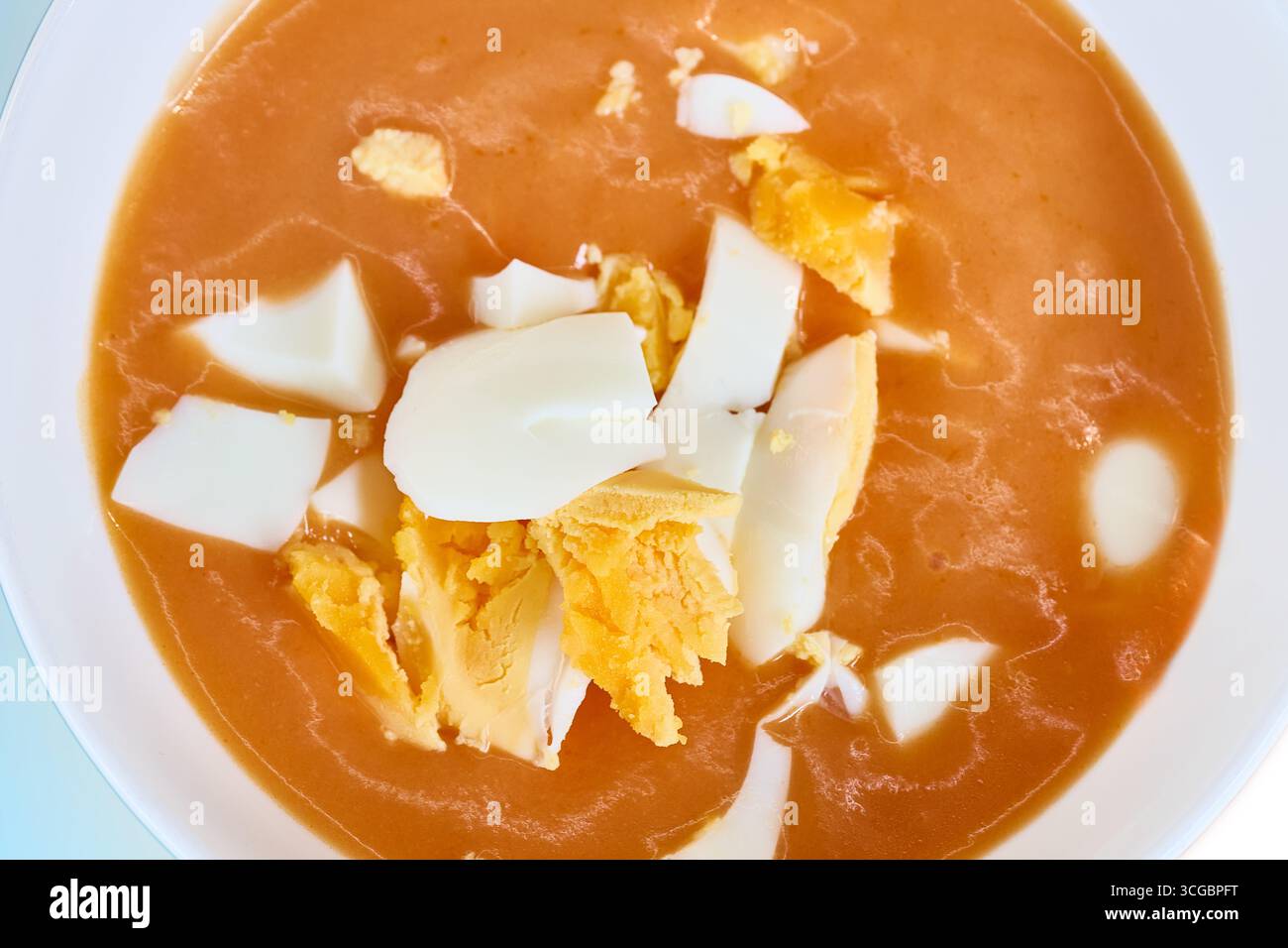 Primo piano di una ciotola di salmorejo rinfrescante, una tradizionale zuppa fredda spagnola, condita con uova sode tritate Foto Stock