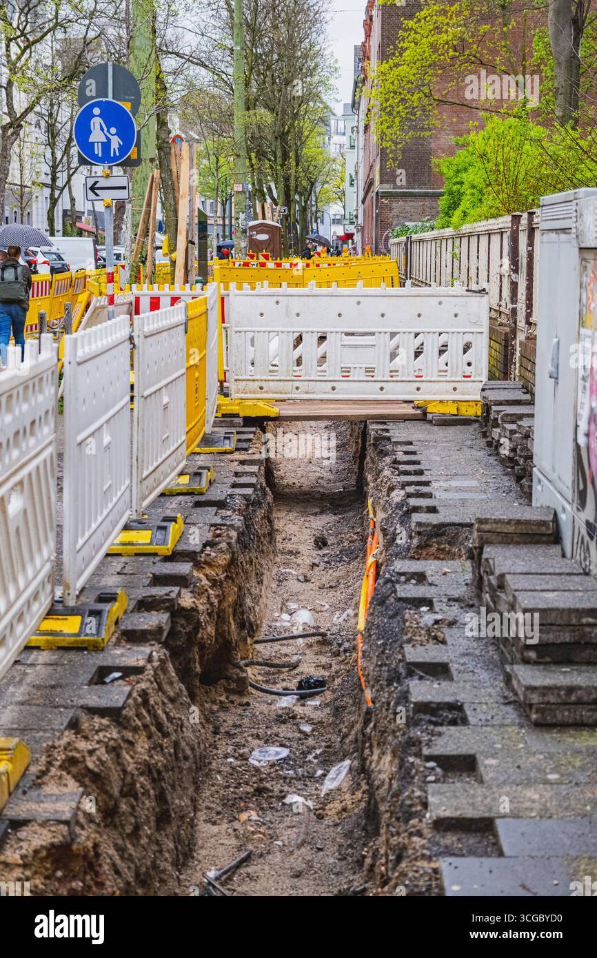 Ricostruzione del marciapiede con barriere di sicurezza posizionate intorno al sito di scavo Foto Stock