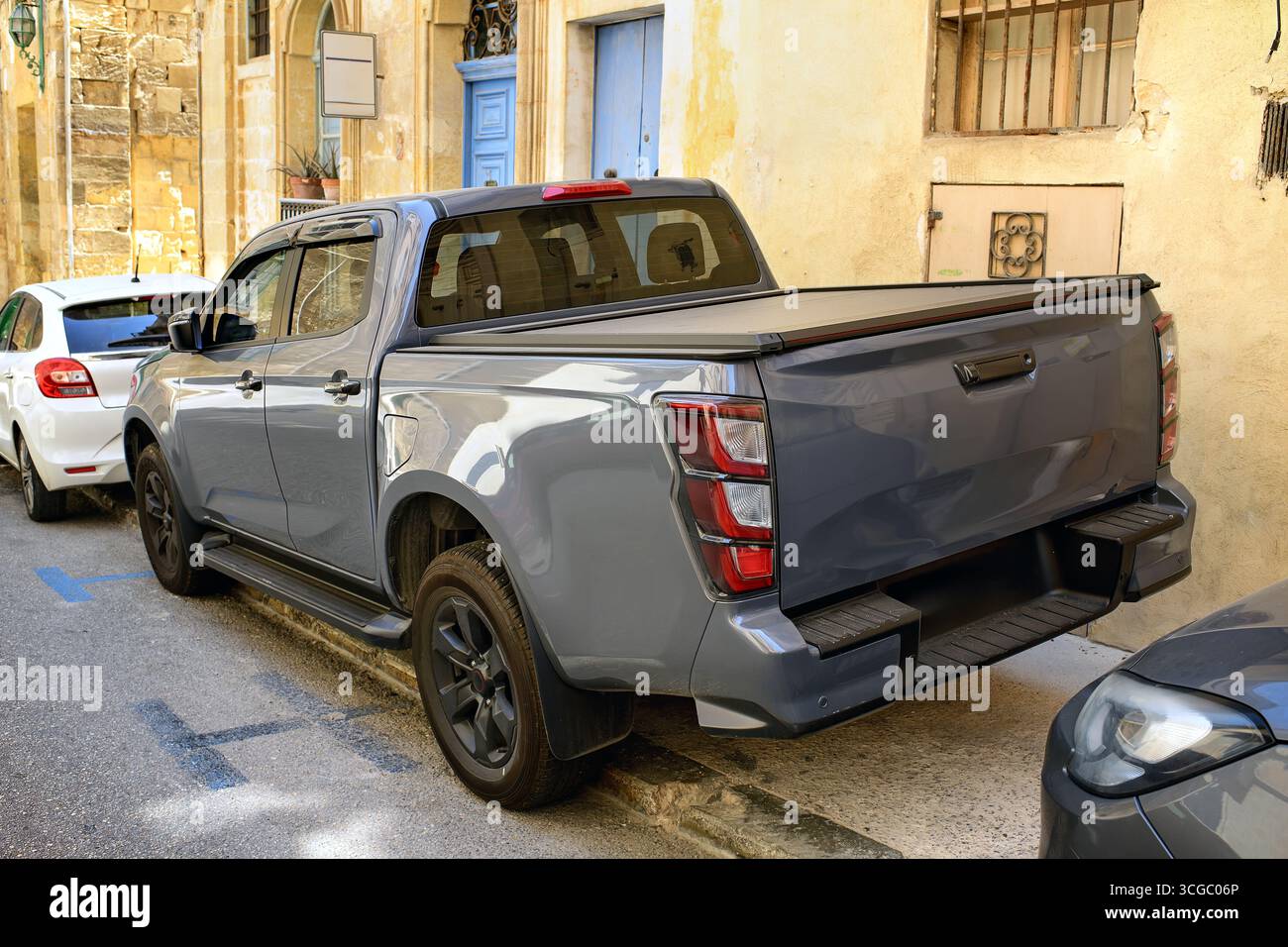 Pick-up SUV con pianale di carico chiuso parcheggiato su un marciapiede di una strada stretta vicino a una casa. Vista dell'angolo laterale posteriore che mostra le luci di posizione posteriori, le ruote e lo specchietto anteriore. Foto Stock